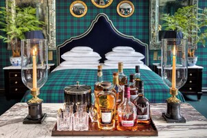 A luxurious bedroom with a large bed, a tray of liquor bottles, and candle holders.