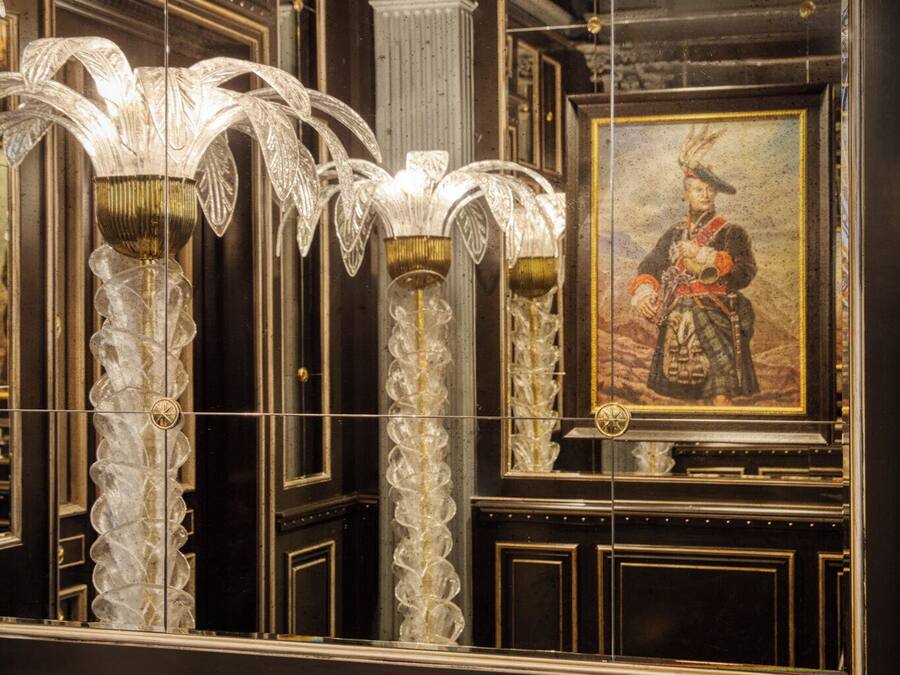 Ornate columns with intricate designs, a framed portrait, and detailed wall paneling.