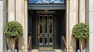 A grand entrance with columns, a sign reading "100 PRINCES STREET," and two symmetrical topiary bushes. - 100 Princes Street (Edinburgh)