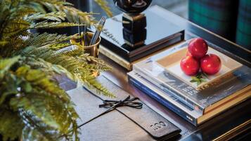 A table with a plant, books, a black leather notebook, and a plate with apples.