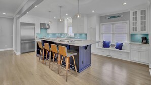 A modern kitchen with a central island, bar stools, and pendant lighting. - Award-Winning Resort Amenities | Yacht Harbor Court 31 (Isle of Palms)