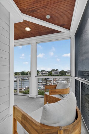 Ein Balkon mit Holzstühlen und Blick auf eine Marina.