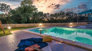 Ein Poolbereich mit Steinmauer, Liegestühlen und einer Gitarre.