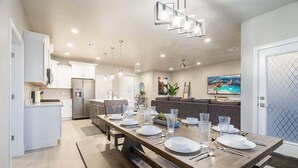 A modern kitchen with white cabinets, a dining table set for six, and a large window overlooking a pool. - Zion Village Poolhouse (From $299) Sleeps 24 * Spa (Hurricane)