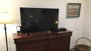 A wooden dresser with a flat-screen TV on top, a lamp to the left, and a framed picture on the wall. - American Charm • King Bed & Kitchen Downtown (Cleveland)