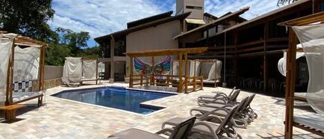 Zona de piscina con sillones de descanso y una zona de estar cubierta.