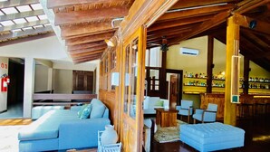 Um interior amplo com teto de madeira, espaço de bar e diferentes disposições de assentos.