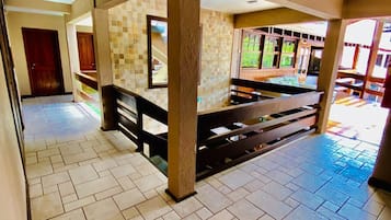 A spacious lobby with a tiled floor, a central column, and a staircase leading to upper levels.