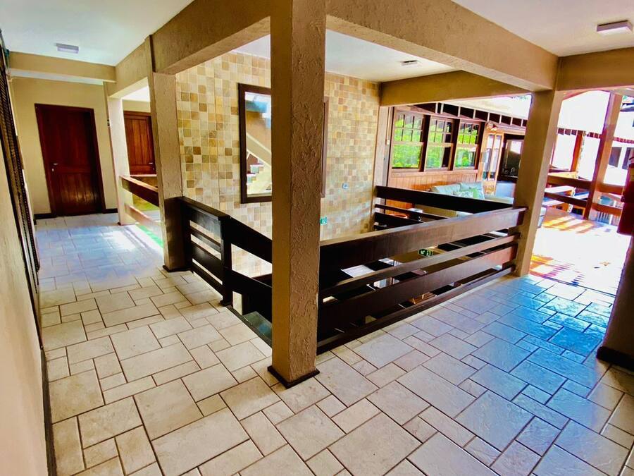 A spacious lobby with a tiled floor, a central column, and a staircase leading to upper levels.