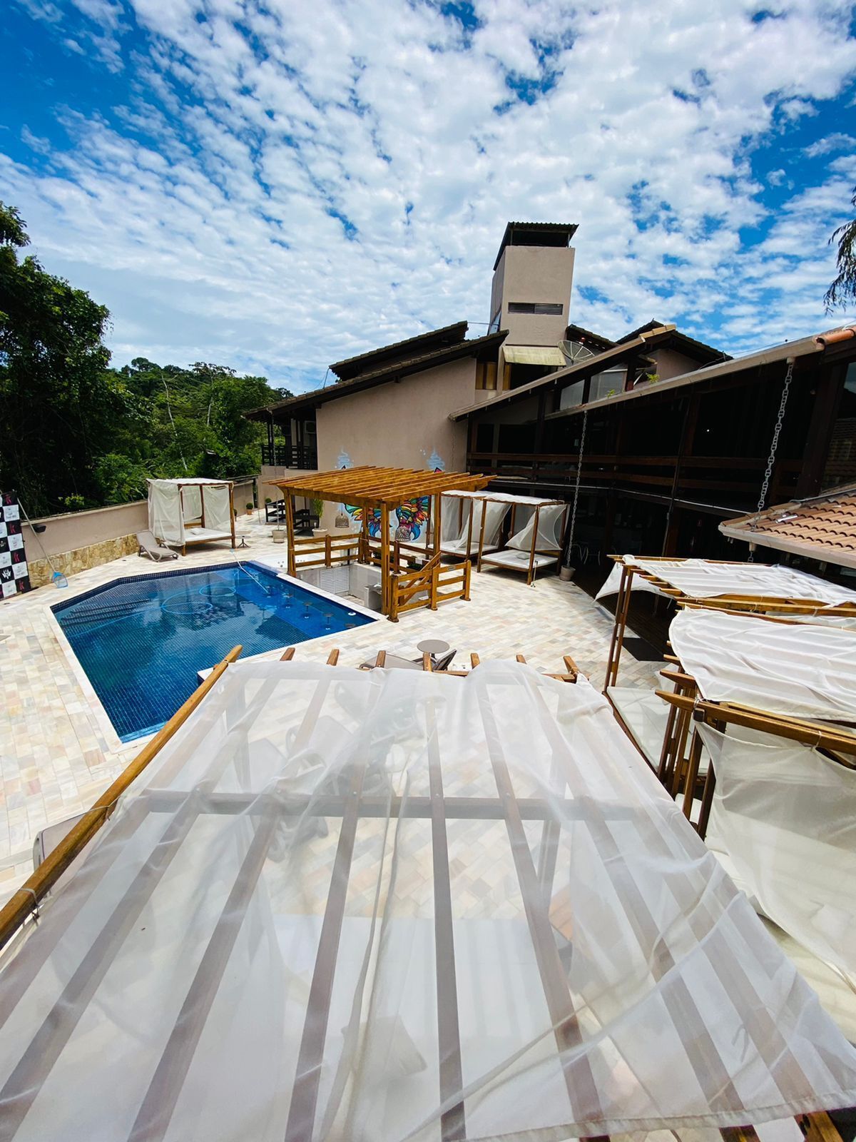 A swimming pool with a wooden deck, lounge chairs, and a pergola.