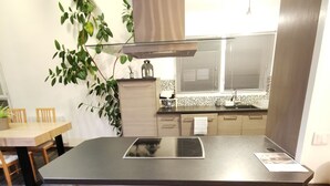 Une cuisine moderne avec un îlot central, des tabourets de bar et une plante en pot.