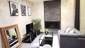 Un salon moderne avec un téléviseur à écran plat, un canapé, une table basse et une cheminée.