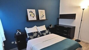 Une chambre à coucher comprenant un lit, des tables de chevet, une commode et des œuvres d’art murales.