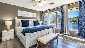 Une chambre à coucher avec un lit, une table de chevet, une lampe et une vue sur un lac.
