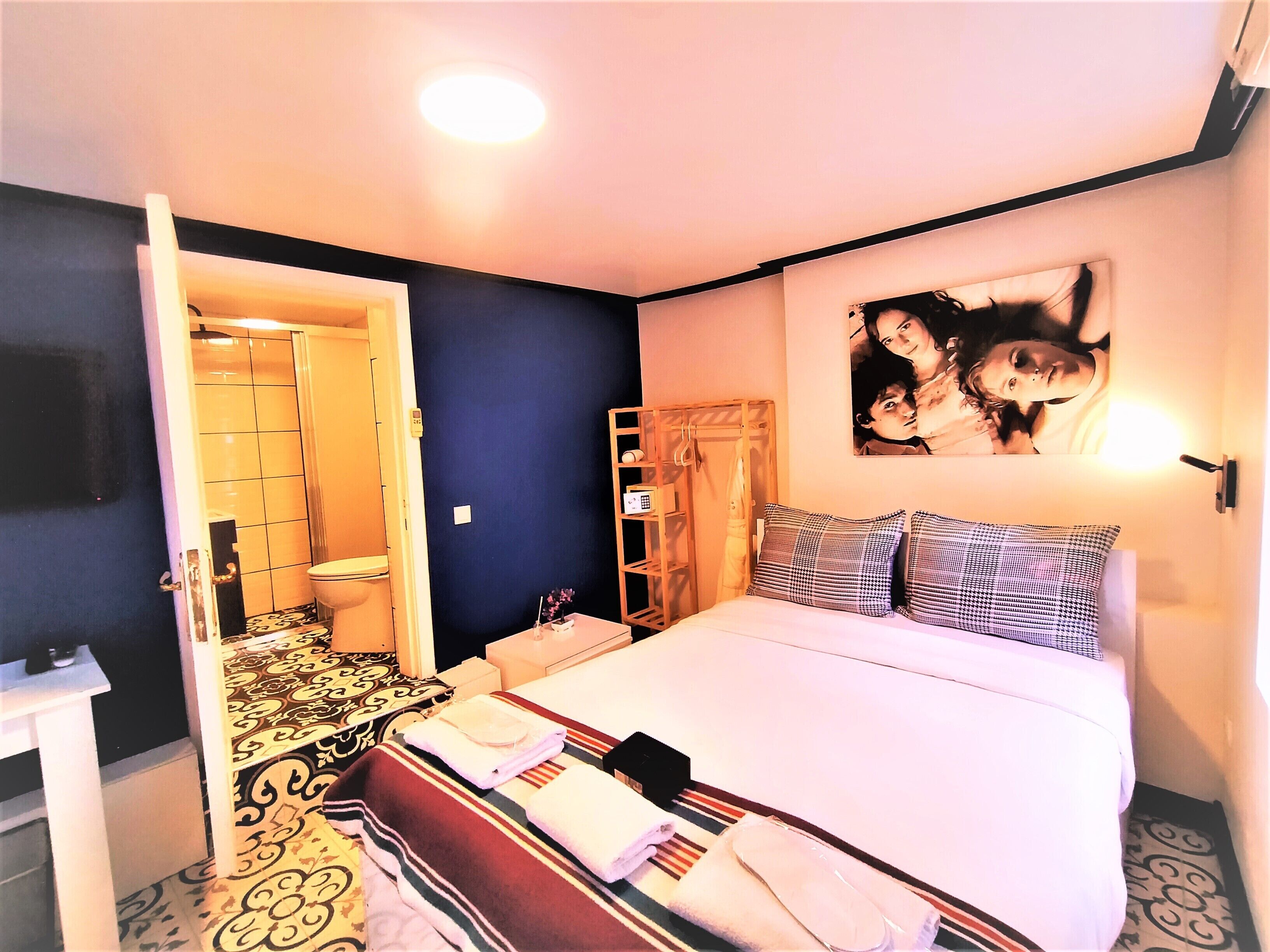 A hotel room with a bed, a bathroom, a wardrobe, and a wall-mounted TV.