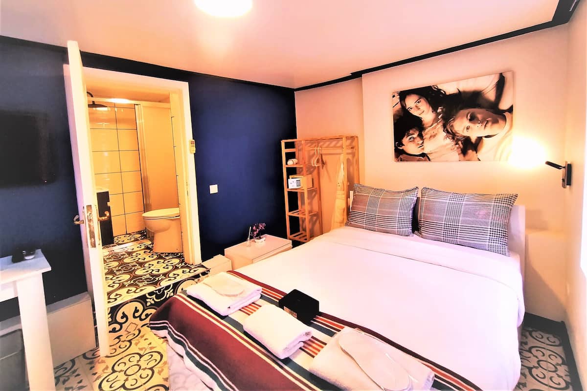 Habitación de hotel con cama, baño, armario y televisor de pared.