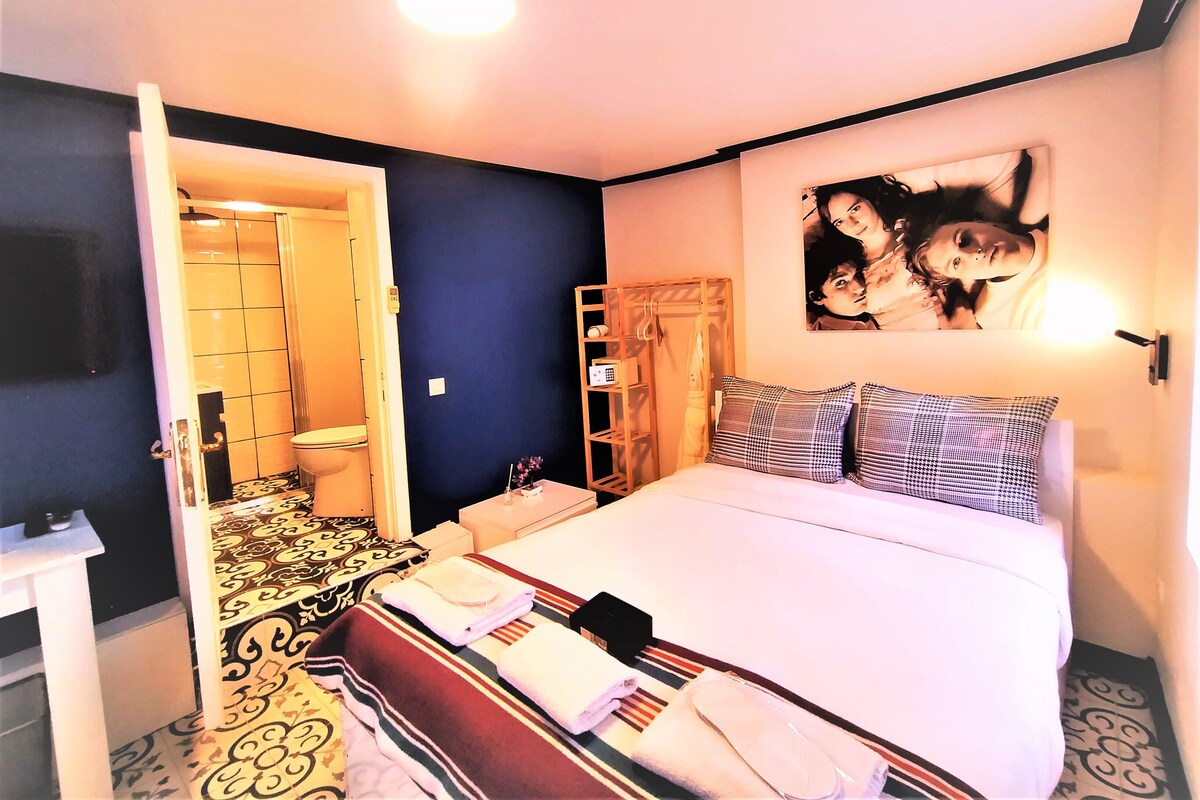 A hotel room with a bed, a bathroom, a wardrobe, and a wall-mounted TV.