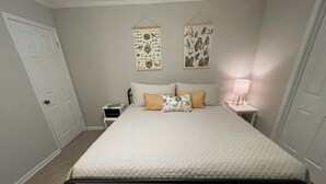 Un dormitorio con cama, dos mesitas de noche, una puerta y adornos en la pared.