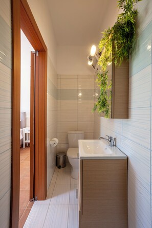 Une salle de bain moderne avec une porte en bois, des carreaux blancs, un lavabo et des toilettes.