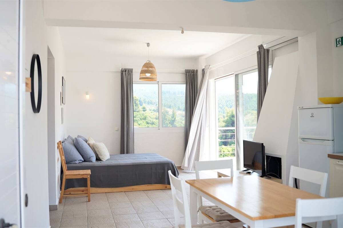 Un dormitorio acogedor con cama, mesita de noche y vistas a la vegetación por la ventana.