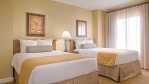 A hotel room with two beds, a lamp, and a window with curtains.
