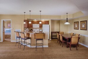A compact kitchen with a central island, bar stools, and a dining table with chairs. - Enjoy the luxury & excitement of Lake Buena Vista with a splash of Disney Magic (Lake Buena Vista)