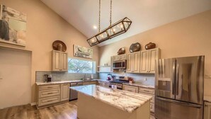 A modern kitchen with a large island, stainless steel appliances, and light wood flooring.