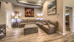 A living room with a sectional sofa, a coffee table, and a painting on the wall.