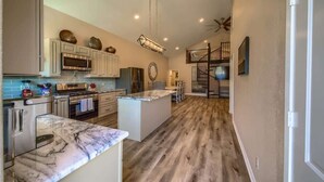 A spacious kitchen with a central island, built-in appliances, and a wooden floor.