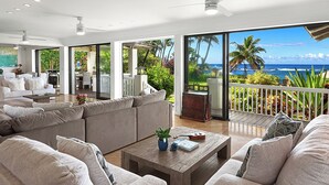 Un vaste espace de vie agrémenté d’une grande fenêtre donnant sur un jardin tropical et offrant une vue sur l’océan.