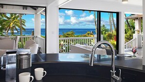 Une cuisine moderne dotée d’une grande fenêtre donnant sur un balcon avec vue sur l’océan.
