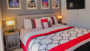 A neatly arranged hotel room with a bed, two bedside tables, a TV, and framed pictures on the wall. - The Glenbrook Getaway – 4BR Resort Home with Pool & Spa (Four Corners)