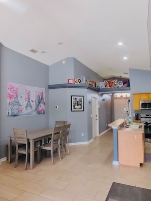 A modern kitchen with a built-in oven, a dining area with a table and chairs, and a wall with a framed picture.