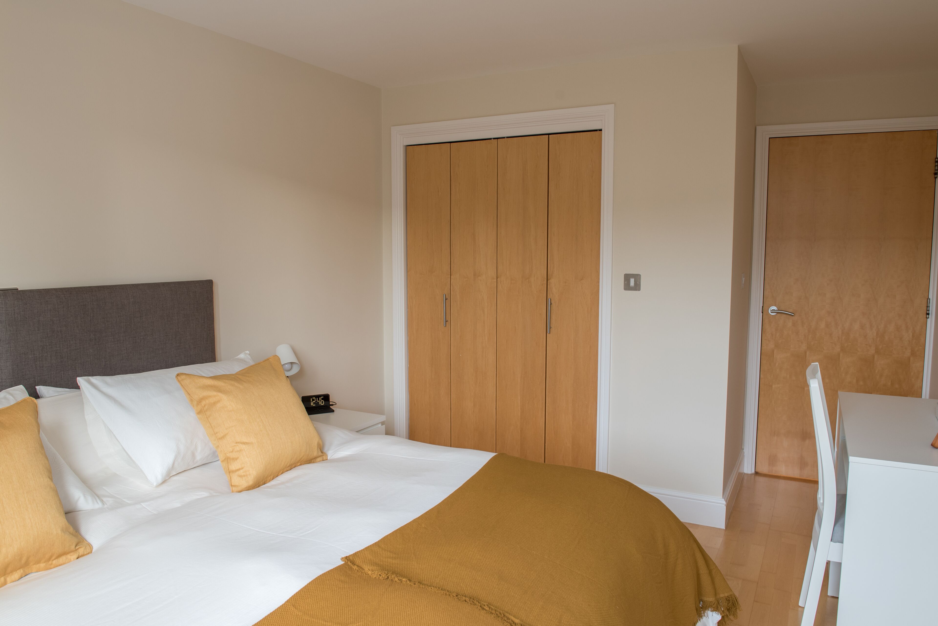 A bedroom with a bed, a wardrobe, and a desk with a chair.
