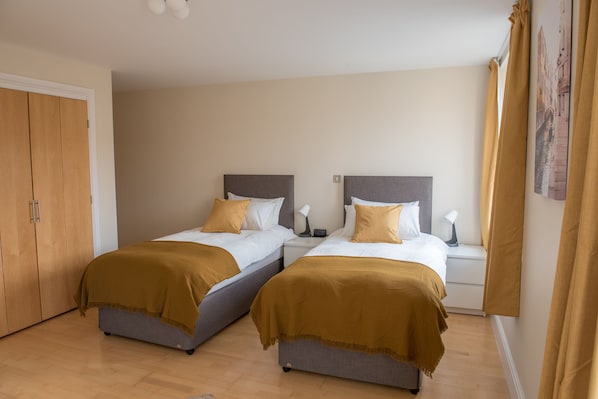 A double room with two beds, each with a headboard, bedside tables, and lamps.