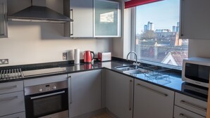 Una cocina moderna con electrodomésticos de acero inoxidable, una ventana con persiana roja y vistas a la ciudad.