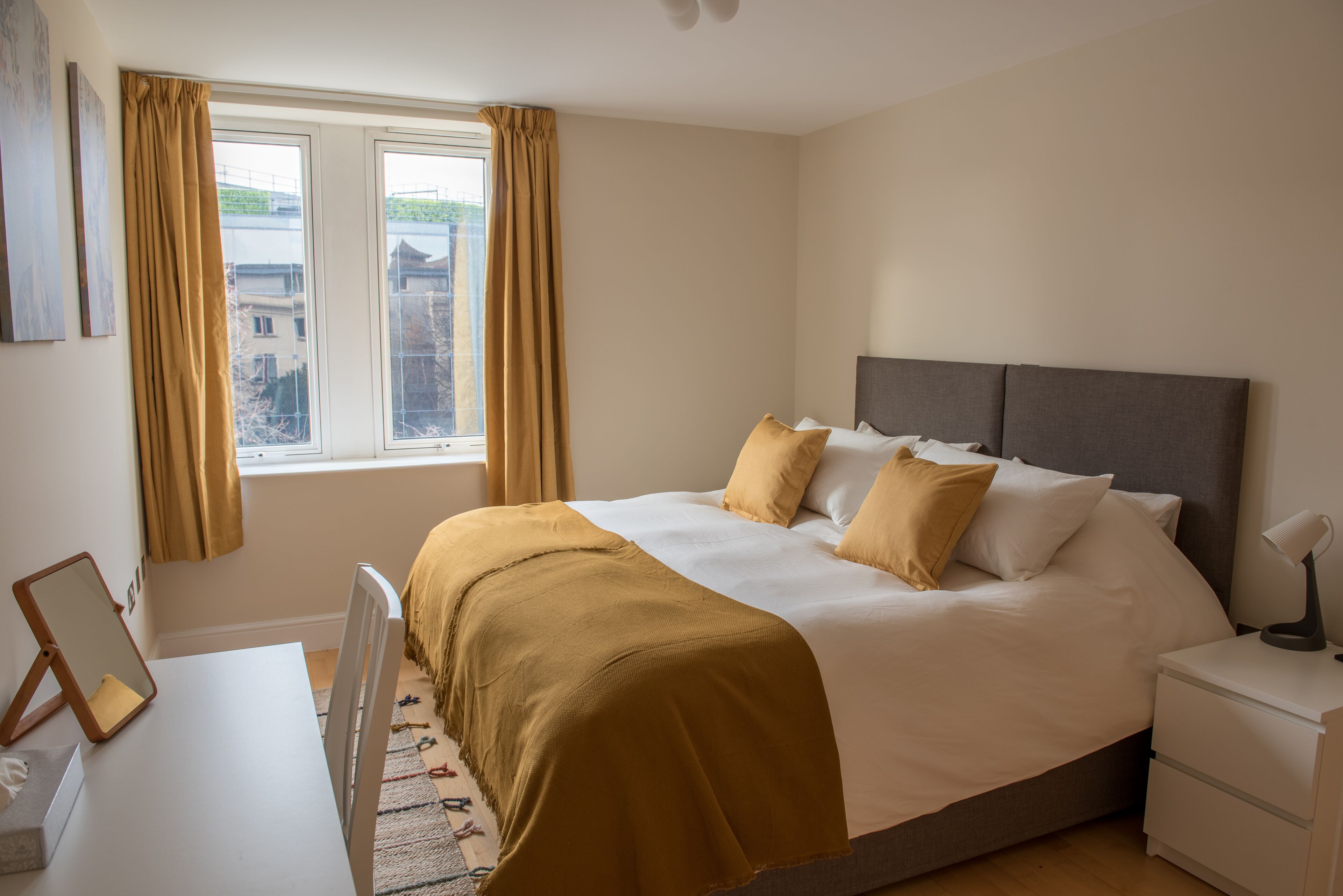 Una camera da letto ordinata con un letto, comodini e una finestra con tende.