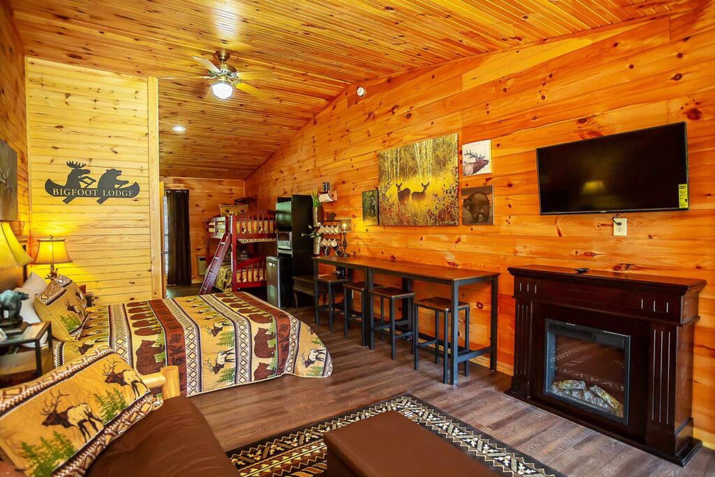 Un intérieur chaleureux et accueillant, avec des murs en bois, une cheminée, un téléviseur et un coin repas.