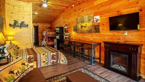 Ein gemütliches Lodge-Interieur mit Holzwänden, Kamin, Fernseher und Essbereich.