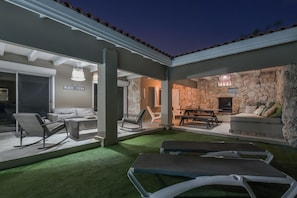 Un espace extérieur aménagé en terrasse, avec des sièges et un mur en pierre en arrière-plan.