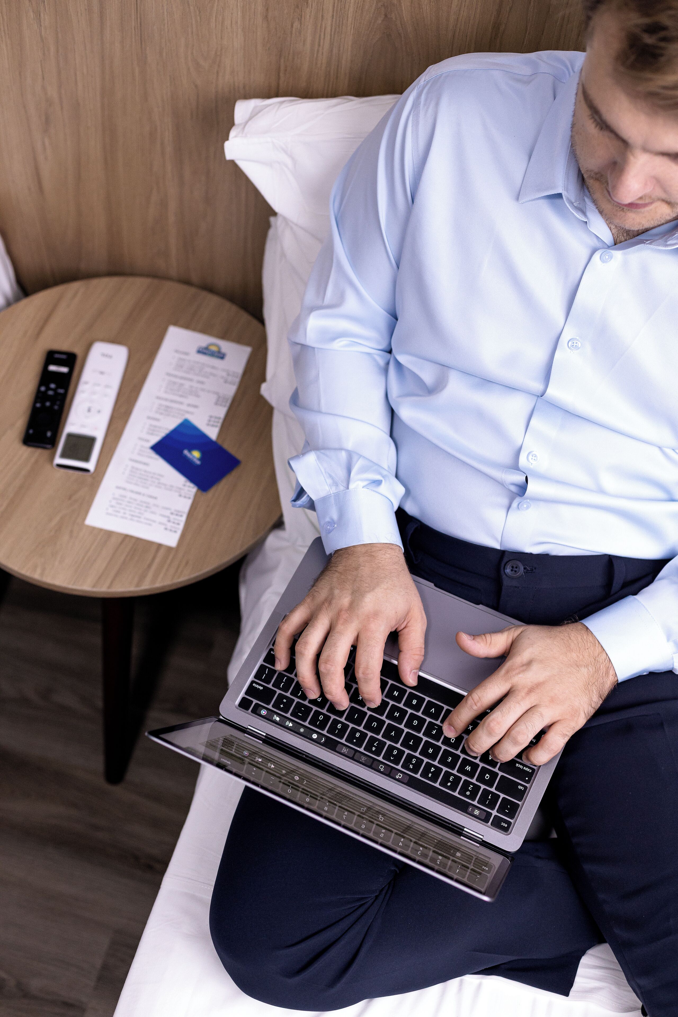 A person using a laptop on a bed in a hotel room.