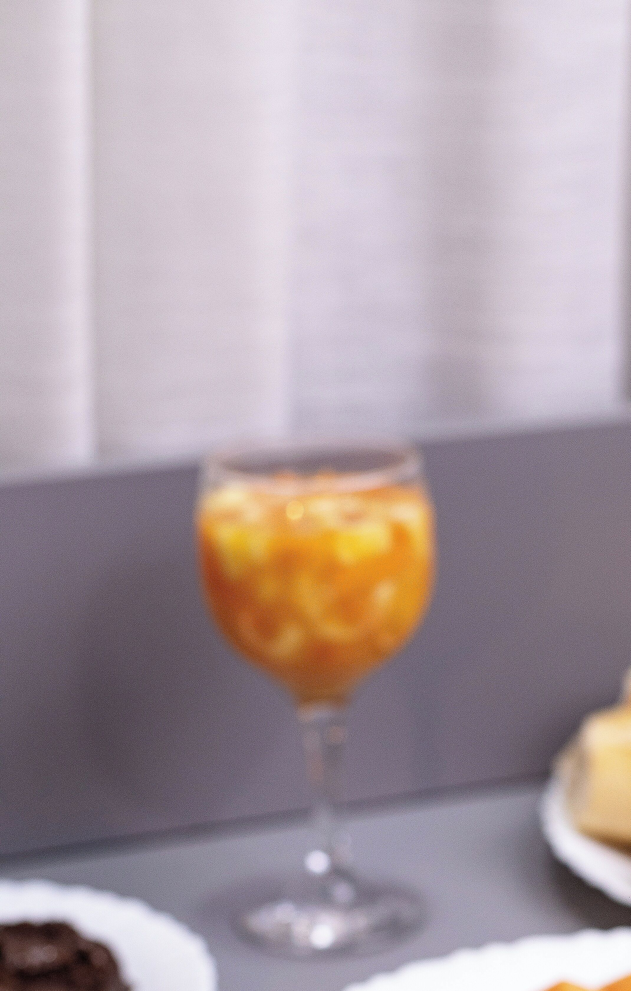 Una mesa de comedor con un vaso de jugo de naranja y un plato de comida.