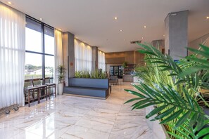 A spacious lobby with a marble floor, seating area, large windows, and indoor plants. - Days Inn By Wyndham Cascavel (Cascavel)
