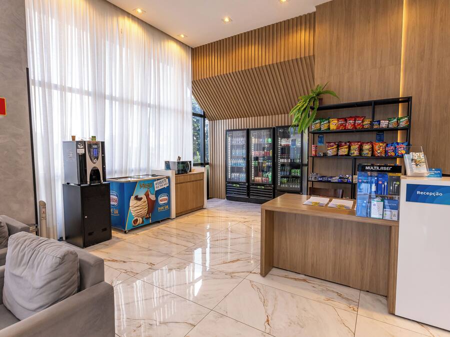 A hotel reception area with a marble floor, a reception desk, a coffee machine, a snack shelf, and a seating area with a couch.