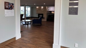 A spacious lobby with a stone accent wall, a seating area with a round table, and directional signs for various hotel rooms and amenities. - Baymont By Wyndham Dayton North (Dayton)
