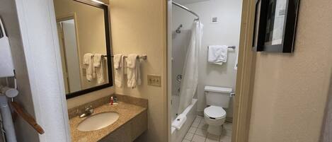 A bathroom with a sink, mirror, and a shower area.