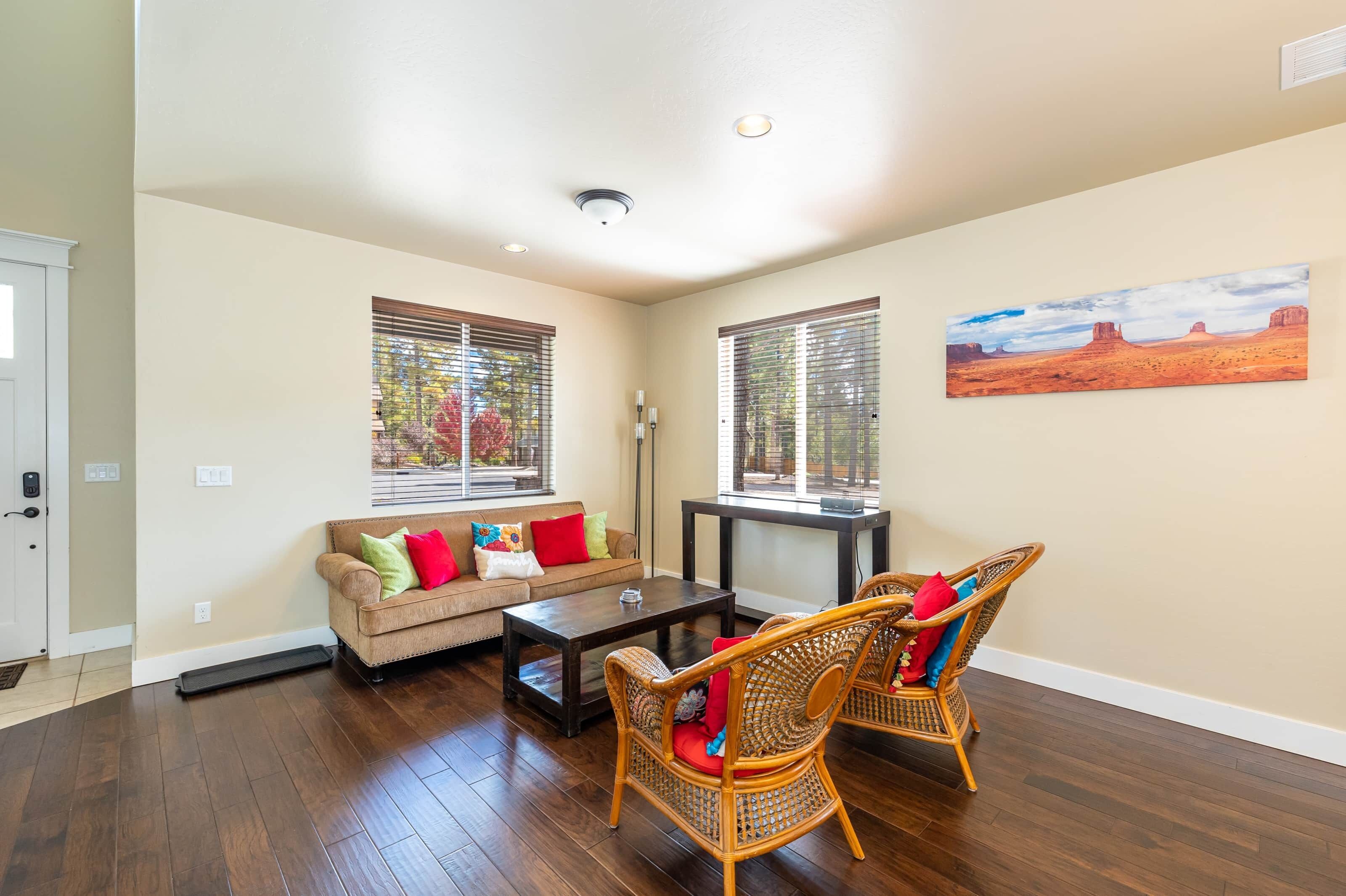 A living room with a sofa, coffee table, wicker chairs, and a painting on the wall.
