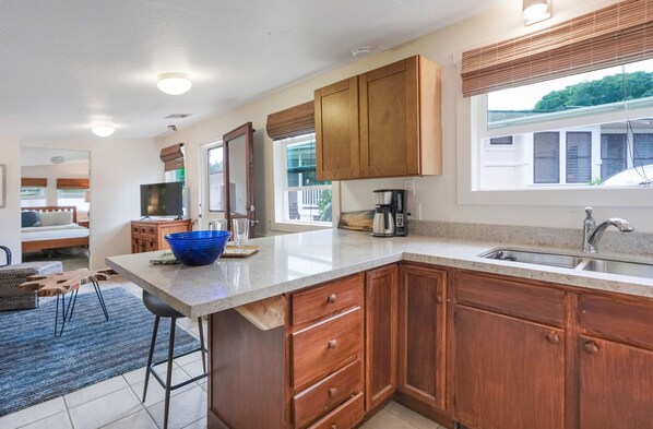 A modern kitchen with wooden cabinets, a granite countertop, and a built-in coffee maker. - Five Bed, Five Bath Tropical Paradise With A/C, Hot Tub, & Beach Walk (Koloa)