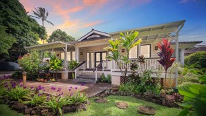 A two-story house with a covered porch, a staircase, and a garden with various plants and flowers. - Five Bed, Five Bath Tropical Paradise With A/C, Hot Tub, & Beach Walk (Koloa)