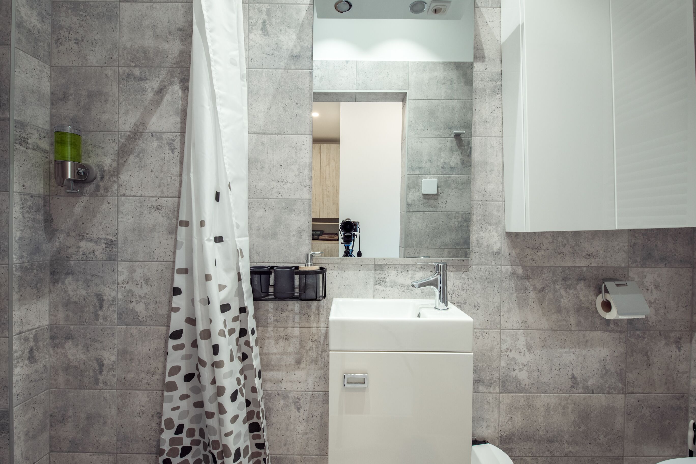 Un baño moderno con ducha, lavabo y espejo.